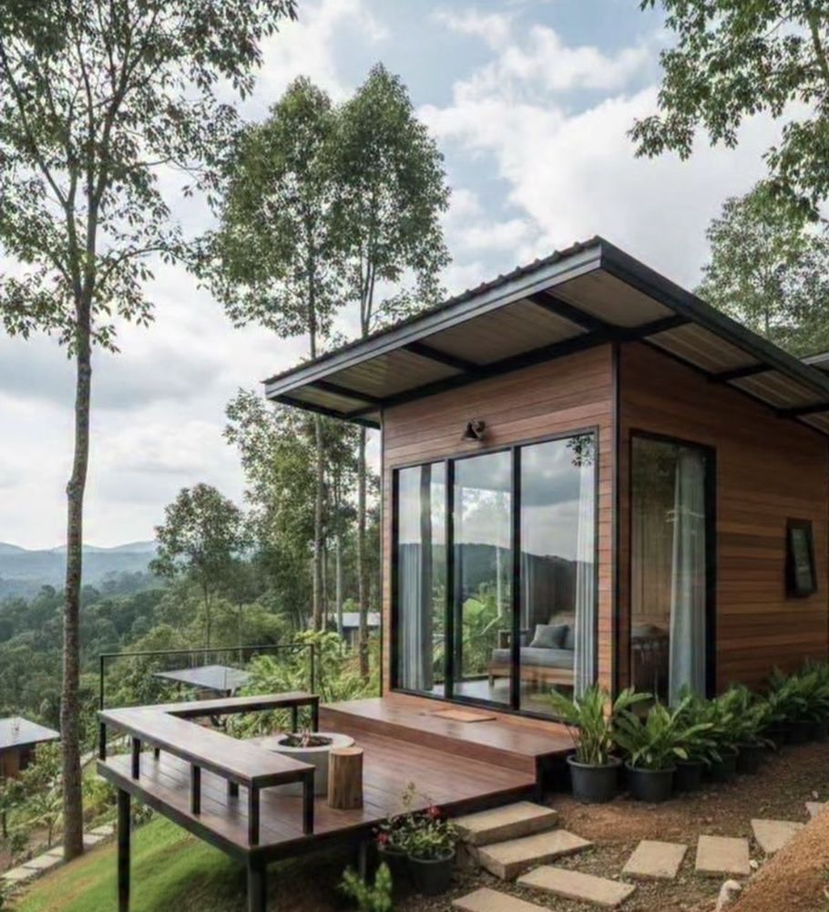 Cabaña de madera con grandes ventanales y terraza rodeada de árboles